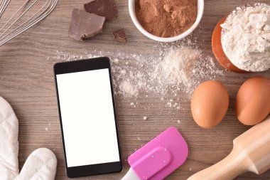 Pasta malzemeler mobile ile ahşap bir masaya. Dijital kitap tariflerde kavramı. Yatay kompozisyon. Üstten görünüm