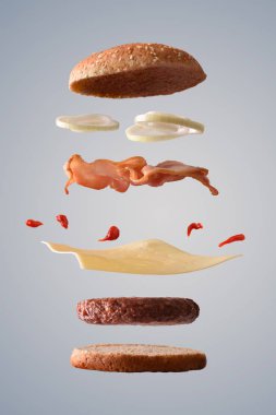 Klasik sığır eti burger pastırma soğan ve peynir gri degrade izole arka plan üzerinde yerlerinde kırık aşağı malzemelerle yüzer. Önden görünüm. Dikey kompozisyon.