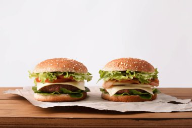 İki klasik biftek burger peynir ve domates ve soğan ve beyaz backgorund ile ahşap masa üzerinde pastırma ile. Önden görünüm. Yatay kompozisyon.
