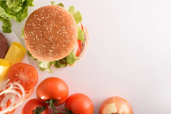 Homemade beef burger with ingredients on white table. Top view. Horizontal composition.