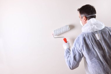 Arka plan iş yarı tulumlar ve silindir üzerinde beyaz bir duvar arkası ile profesyonel ressam ile. Ressam ve boya malzemeleri kavramı. Yatay kompozisyon.