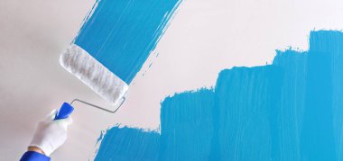 Profesyonel ressam el ile silindir beyaz bir duvar üzerinde mavi bir örnek resim. Yatay kompozisyon.