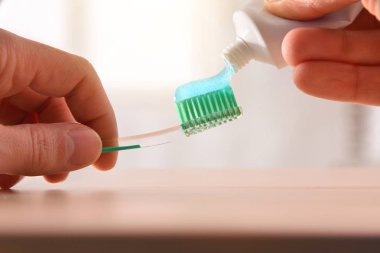 Man putting toothpaste on a toothbrush for oral cleaning clipart