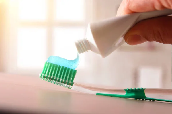 Concept oral hygiene with hand putting toothpaste on toothbrush — Stock Photo, Image