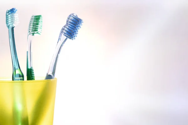 Limpeza dental diária com copo de plástico amarelo com escovas de dentes — Fotografia de Stock