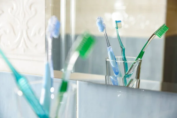 Toothbrushes in vase reflected in the glass of a bathroom — Stock Photo, Image