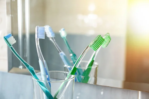 Toothbrushes in a glass vase in bathroom reflected in mirror — Stock Photo, Image