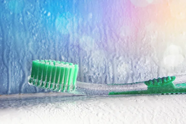 Toothbrush on a bath and water spray with colored lights — Stock Photo, Image