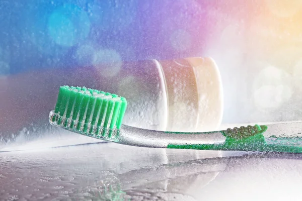 Toothbrush on a washbasin and water spray with colored lights — Stock Photo, Image