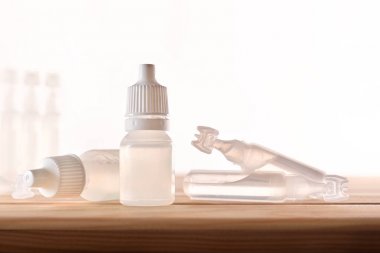 Ahşap masa üzerinde göz ilaç ile plastik şişe ve pipetler