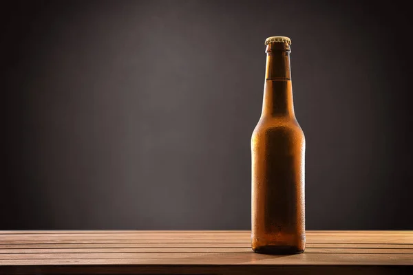 Beer bottle filled and closed on wood table black background. — Stock Photo, Image