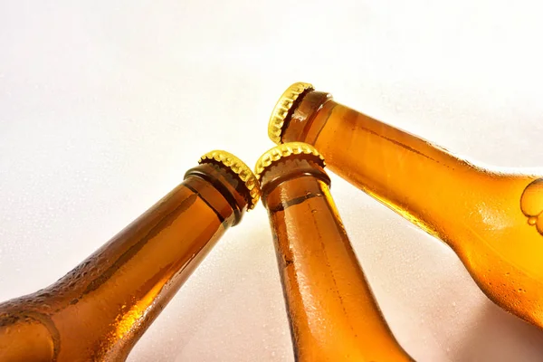 Três gargalos preenchidos com cerveja fresca fechada na mesa branca — Fotografia de Stock