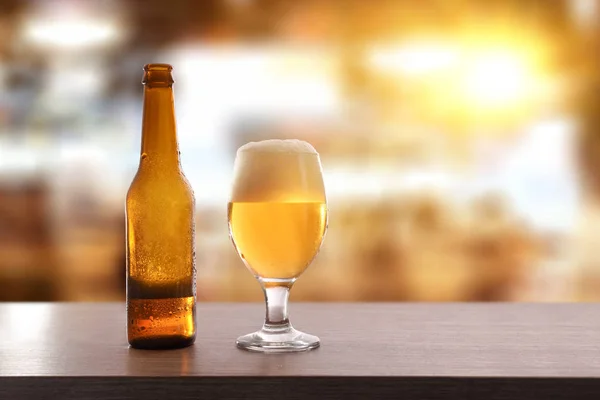 Beer bottle and glass cup on table in leisure place