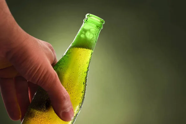 Hand hållande flaska full av öppen alkoholhaltig dryck grön bakgrunds — Stockfoto