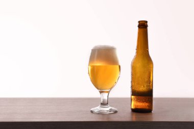 Bira şişesi ve cam bardak masada izole beyaz