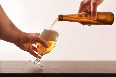Eller ahşap masa izole beyaz bir bira bardağı doldurma