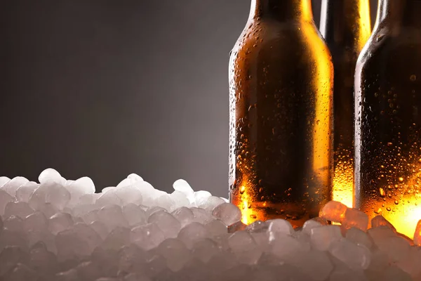 Três garrafas de cerveja cheias no gelo e fundo preto detalhe — Fotografia de Stock