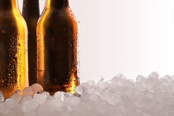 Três garrafas de cerveja cheias no gelo e fundo branco detalhe — Fotografia de Stock