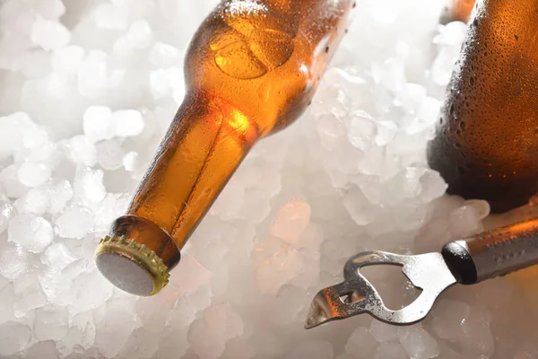 Garrafa de cerveja deitada em gelo picado com abridor de garrafas — Fotografia de Stock
