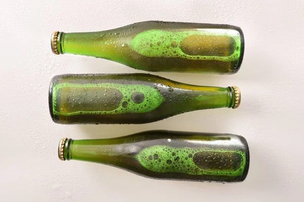 Drie groene flessen met alcoholische drank op wit tafelblad — Stockfoto