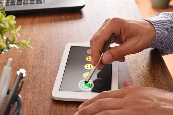 Hombre proporcionando una evaluación sobre un dispositivo electrónico en el escritorio — Foto de Stock