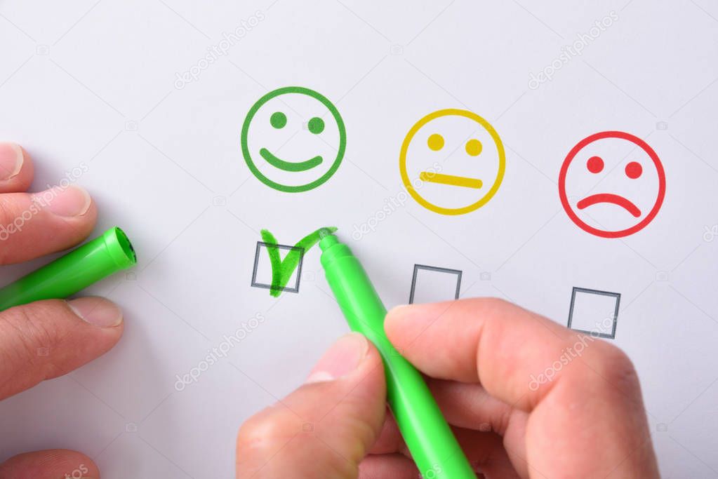 Hand marking a positive satisfaction represented with emoticons 