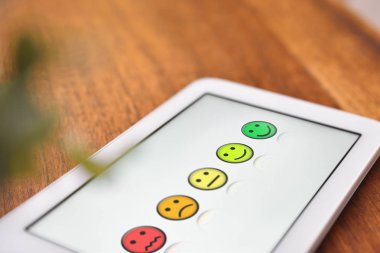 Ahşap masa üzerinde beyaz tablet üzerinde memnuniyet gösterimi yükseltmek
