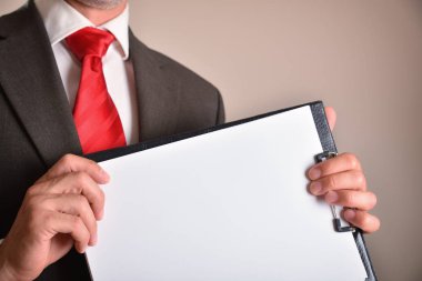 Ön tarafta boş çarşaflar olan bir klasörü gösteren takım elbiseli adam