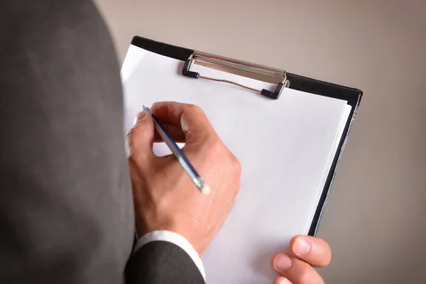 Man dressed on his back taking notes in a folder — Stock Photo, Image
