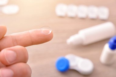 Arka plan bakım ürünü ile parmak üzerinde lens ile el