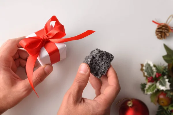 Hands with coal and christmas gift reward concept for behavior