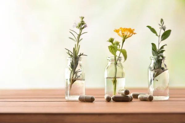 Naturliga växtbaserade medicin kapslar på träbord med trädkrukor — Stockfoto