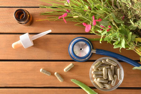Natural medicine capsules on table with pants and stethoscope to