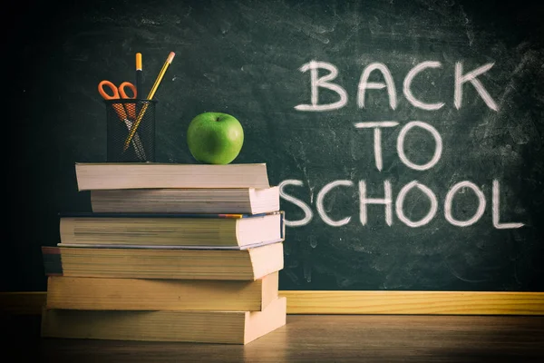 学校のメッセージをバックに背景に緑の黒板とクラステーブルの上に鉛筆とリンゴと本のスタック 勉強の概念 — ストック写真