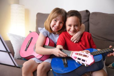 Gülen kız ve oğlan oturma odasındaki kanepede otururken gitar çalışırken yakalandı.