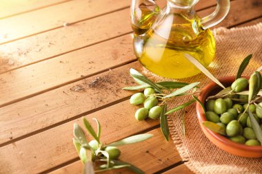 Zeytin yağıyla dolu bir konteynır ile ahşap bir masanın üzerindeki ağaçtan zeytinler. Yüksek görünüm.