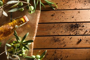 Zeytin yağlı cam şişe, dallı ve zeytinli ahşap masa. Karşıt görüntü. Üst görünüm.