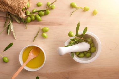 Vücut ve mutfak bakımı için hazırlanmış seramik bardakta zeytinyağı tohumu havan ve zeytin çuvalı ile birlikte masada. Üst görünüm.