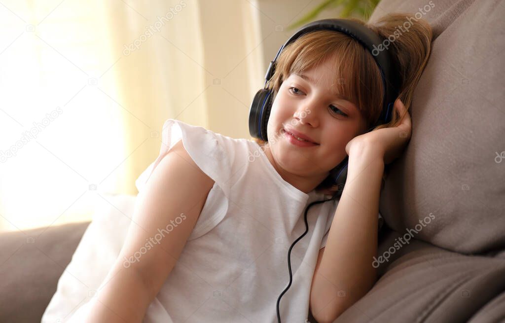 Girl with helmets listening to music sitting on the sofa at home in a quiet and warm environment