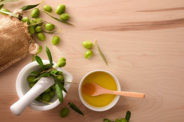 Vücut ve mutfak bakımı için seramik bardakta zeytinyağı tohumu hazırlamak için havan ve çuval zeytin. Üst görünüm.