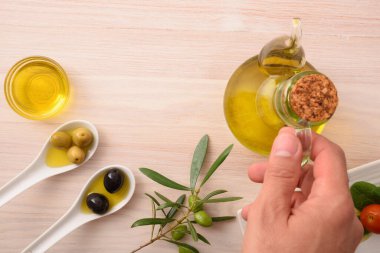 Yemek için farklı zeytin çeşitleri ve ahşap mutfak tezgahındaki kaplarda yağ ve yağ tutucu. Üst görünüm.