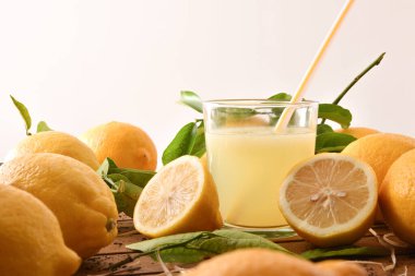 Beyaz izole edilmiş arka planı olan limonlarla dolu ahşap bir masada taze sıkılmış meyve suyu. Ön manzara. Yatay bileşim.