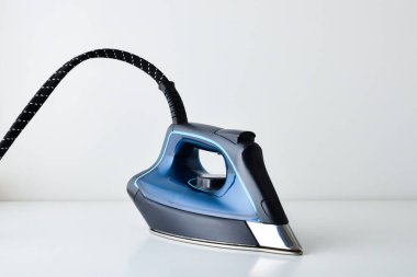 Beyaz masa üzerinde duran mavi buharlı ütünün önden görünüşü ve izole edilmiş beyaz arka plan. Ön görünüm.