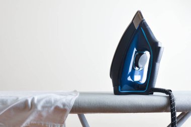 Beyaz gömlekli ve beyaz izole arkaplanlı ütü masasında buhar ütüsüyle ev ütüleme kavramı. Ön görünüm.