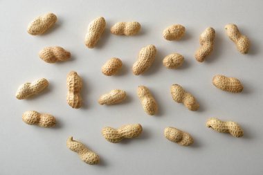 Kahverengi ahşap mutfak masasında, üzerinde meyve ve sebzeler bulunan beyaz bir tabağa fıstık ezmesi sürülmüş taze dilimlenmiş ekmeğin detayları.