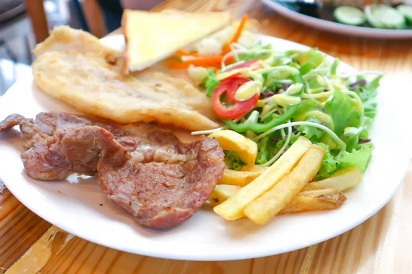 pork steak and fish steak with salad and French fries