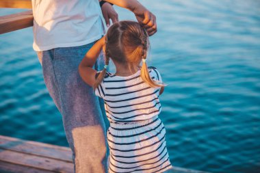 Anne, sıcak yaz aylarında kızının başını denizin arka planına vurur.