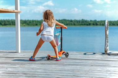 Küçük kız scooter kullanıyor.