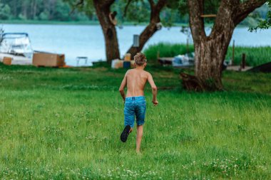 Oğlan göle doğru yeşil çimlerde koşar