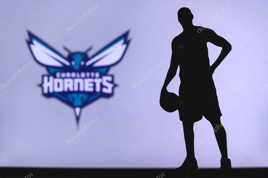 NEW YORK, USA, JUN 18, 2020: Charlotte Hornets logo of professional basketball club in american league. Silhouette of basket player in foreground. Sport concept photo, edit space.